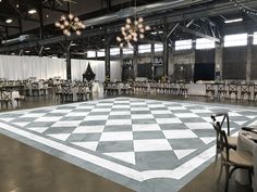 a large checkered dance floor is set up for an event with chandeliers hanging from the ceiling