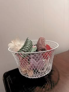 a wire basket filled with assorted cookies on top of a wooden table next to a white wall