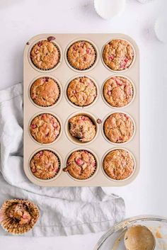 a muffin tray filled with strawberry muffins on top of a white table