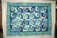 a blue and green quilt hanging from a clothes line