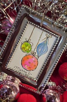 a christmas ornament hanging from a tree with ornaments around it and the words merry written on it