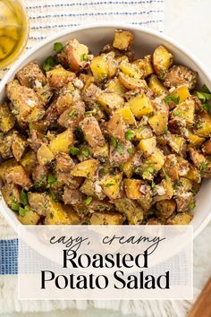 roasted potato salad in a white bowl on a blue and white tablecloth next to a glass of wine