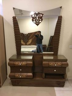 a man taking a photo in front of a large mirror with an ornate design on it