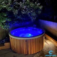 a hot tub lit up at night in the middle of a wooden decked area