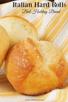 two loaves of bread sitting on top of a yellow and white towel with the words italian hard rolls best holiday bread