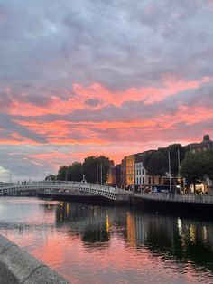 the sky is pink and purple as the sun sets over a river with buildings on both sides