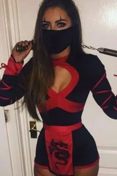 a woman wearing a black and red outfit with a mask on her face, holding a chain around her neck