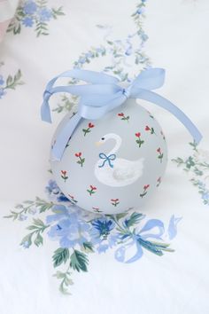 an ornament shaped like a swan on a bed with blue and white flowers