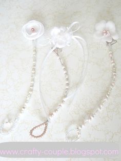 two necklaces with flowers and pearls are on a white tablecloth next to each other