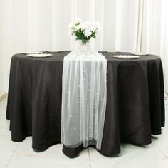 a black table cloth with white flowers in a vase