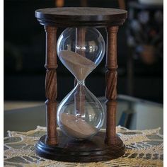 an hourglass sitting on top of a table next to a clock with sand in it