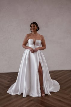 a woman in a white dress standing on a wooden floor with her legs spread out