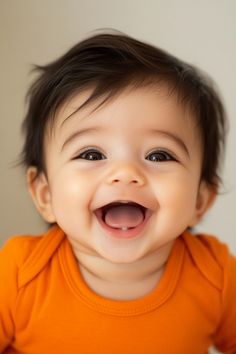 a baby is smiling and wearing an orange shirt