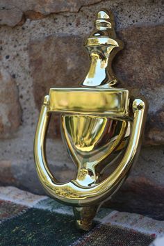 a gold toilet paper holder sitting next to a stone wall