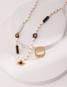 This necklace is a fusion of high-quality materials, including 925 silver, tiger eye stone, black agate, and natural pearls, offering sophistication and charm. Features a multi-material design with a vintage gold hue, varied bead sizes, and a unique eye pendant for a captivating aesthetic. Adjustable length for comfort and style. Add luxury to your jewelry collection. Metal: 18ct Recycled Gold Plated Vermeil on Recycled Sterling Silver Gemstone:Freshwater Pearl/Black Onyx/Tiger Eye Stone Pearl D Gold Tiger Eye, Vintage Gold Rings, Tigers Eye Necklace, Tiger Eye Beads, Eye Pendant, Tiger Eye Stone, Black Agate, Natural Pearl, Eye Stone