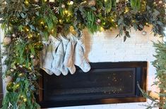 the fireplace is decorated with greenery and stockings