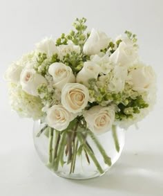 a vase filled with white flowers and greenery