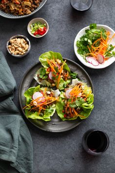 a table topped with plates of food and bowls of salad next to glasses of wine