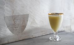 a glass filled with liquid sitting on top of a counter next to a white wall