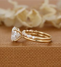 two gold wedding rings sitting on top of each other next to white flowers and petals