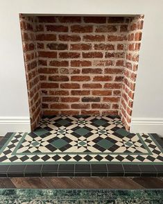 an old brick fireplace in the corner of a room with green and white tiles on it