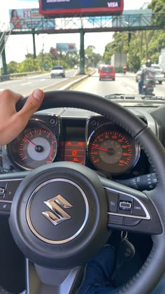 the steering wheel and dashboard of a car on a city street with traffic signs in the background