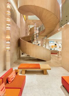 an orange couch sitting in front of a spiral stair case next to a wooden bench