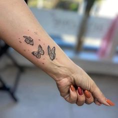 a woman holding the hand of a man with three butterflies tattooed on their left arm