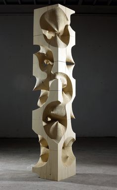 a tall wooden sculpture sitting on top of a cement floor