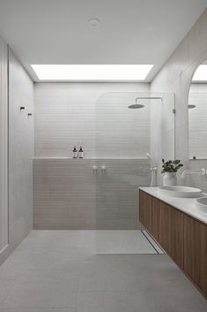 a large bathroom with two sinks and a shower stall in the middle of the room