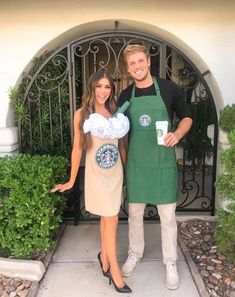 a man and woman standing in front of a gate with starbucks cups on their aprons