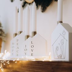 three white candles are sitting on a mantle