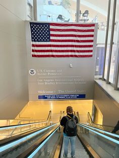 a person riding an escalator with the american flag hanging on it's wall