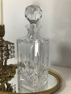 a clear glass bottle sitting on top of a gold tray next to a candle holder