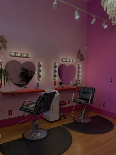 a hair salon with pink walls and mirrors on the wall, two chairs in front of them