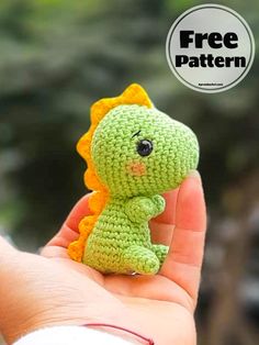 a small crocheted green and orange toy sitting on top of a persons hand