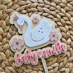 a cake topper that says baby camila with a swan and flowers on it