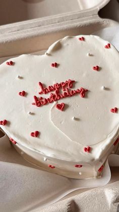 a heart shaped cake with red sprinkles on it sitting in a box