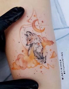 a woman's thigh with a watercolor tattoo of a wolf and the moon