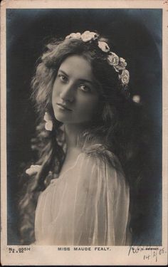 an old black and white photo of a woman with flowers in her hair wearing a dress