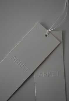 two tags with the word market hanging from strings on a gray background, one is white and the other is black