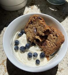 a white bowl filled with yogurt and blueberries on top of a table