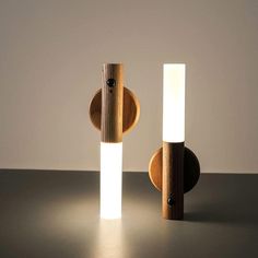 two wooden lights sitting next to each other on top of a black table with a white light in the middle