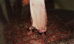 a woman in a long dress standing on a rug