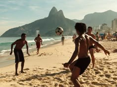 a group of people playing soccer on the beach