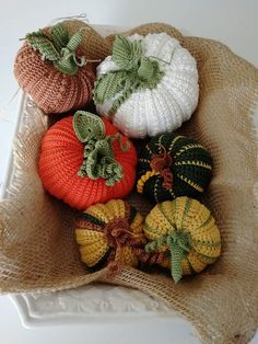 crocheted pumpkins and gourds are sitting on a burlock