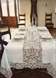 the table is set with white linens and place settings for four people to sit at