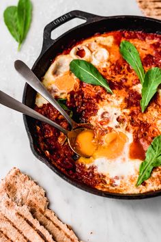 an iron skillet with eggs and spinach on it, next to crackers