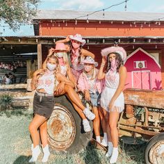 some girls are posing on the back of an old truck in front of a red barn