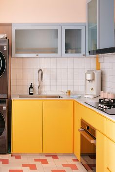 a kitchen with yellow cabinets and white tile flooring is pictured in this image, there are appliances on the counter